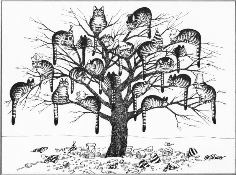 Dozens of cats wearing party hats and costumes sleep in a bare tree, with party debris scattered on the ground below.